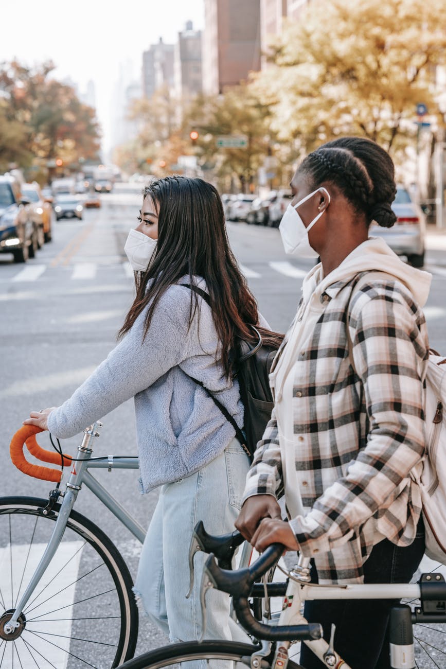 multiracial friends crossing road with bicycles