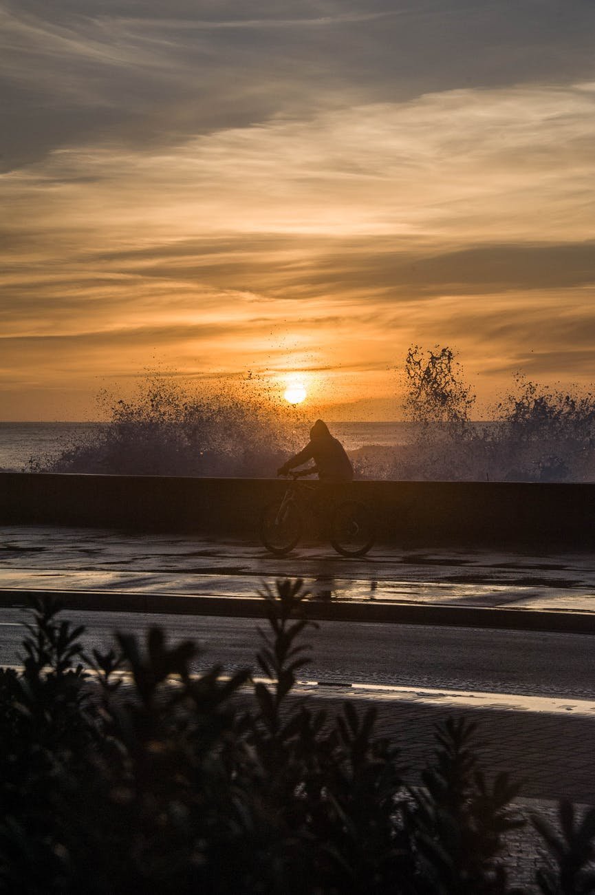 person sitting on snow covered ground during sunset